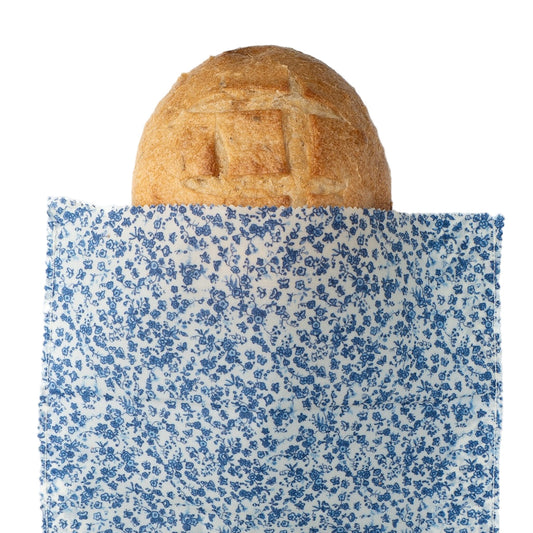 Loaf of bread wrapped in blue floral-patterned beeswax wrap on a white background