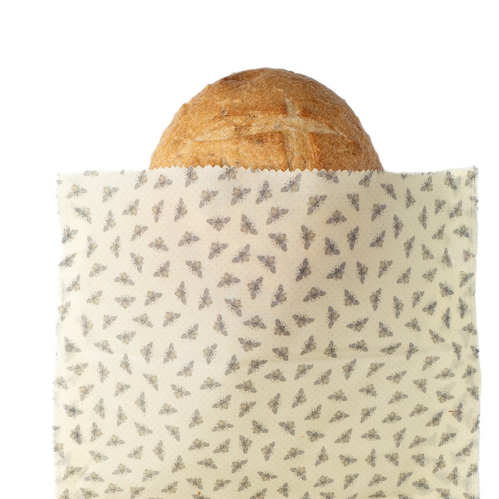 Loaf of bread wrapped in a patterned beeswax wrap on a white background