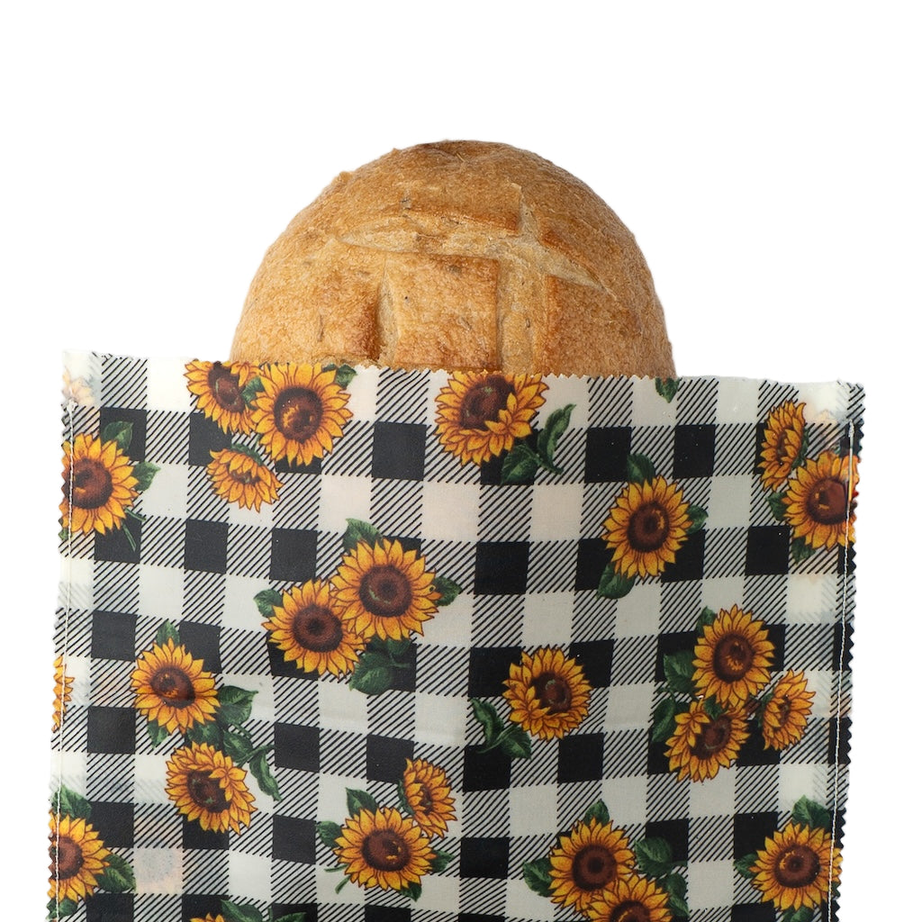Fabric bag with sunflower pattern containing a loaf of bread on a white background